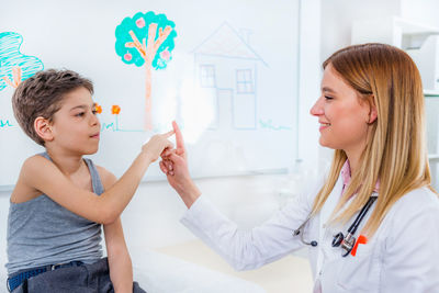 Female doctor playing with boy at clinic