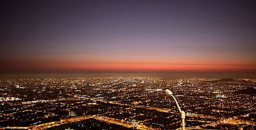 Aerial view of illuminated cityscape against orange sky