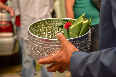 Midsection of man holding religious offerings in bowl