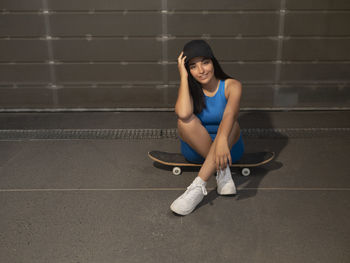 Girl smiles sitting on a skateboard