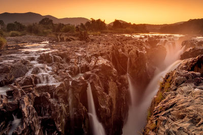 Panoramic view of waterfall against sky during sunset