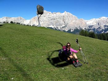 Portrait of woman holding hiking poles while sitting on field