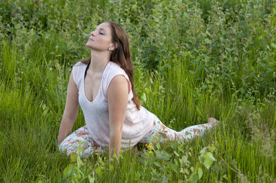 Young woman practicing yoga on grassy field