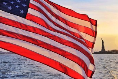 American flag against sea during sunset