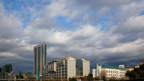 Buildings in city against cloudy sky