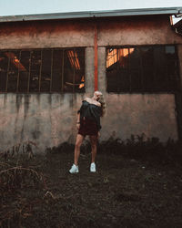 Rear view of woman standing by house