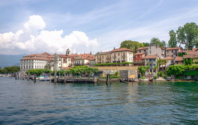 Buildings at waterfront against cloudy sky