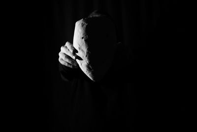 Midsection of person holding leaf in darkroom