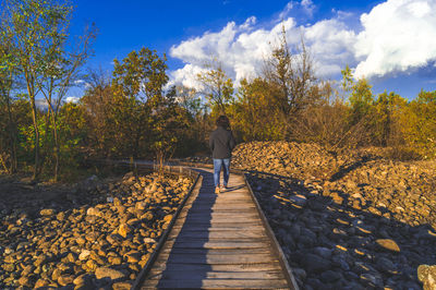 Rear view of woman walking on road amidst trees