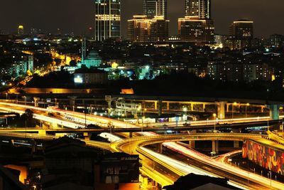 High angle view of illuminated city by buildings at night