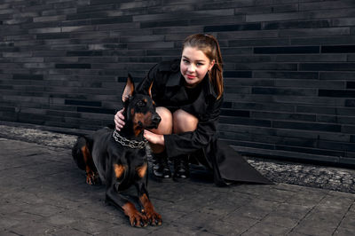 Teenage girl sitting next to a dog on the street. girl hugging her dog in urban environment. 