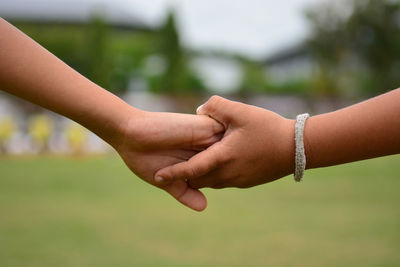 Close-up of friends holding hands outdoors
