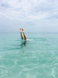 Low section of person in sea against sky