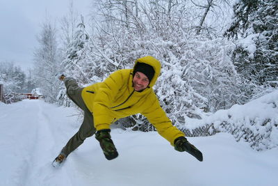 Portrait of man falling on snow against bare trees