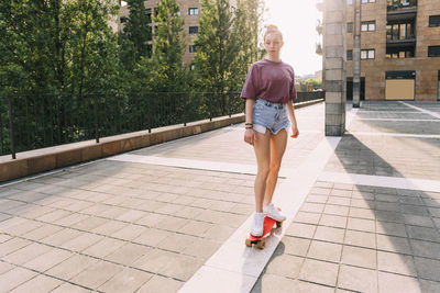 Teenage girl skateboarding on sunny day