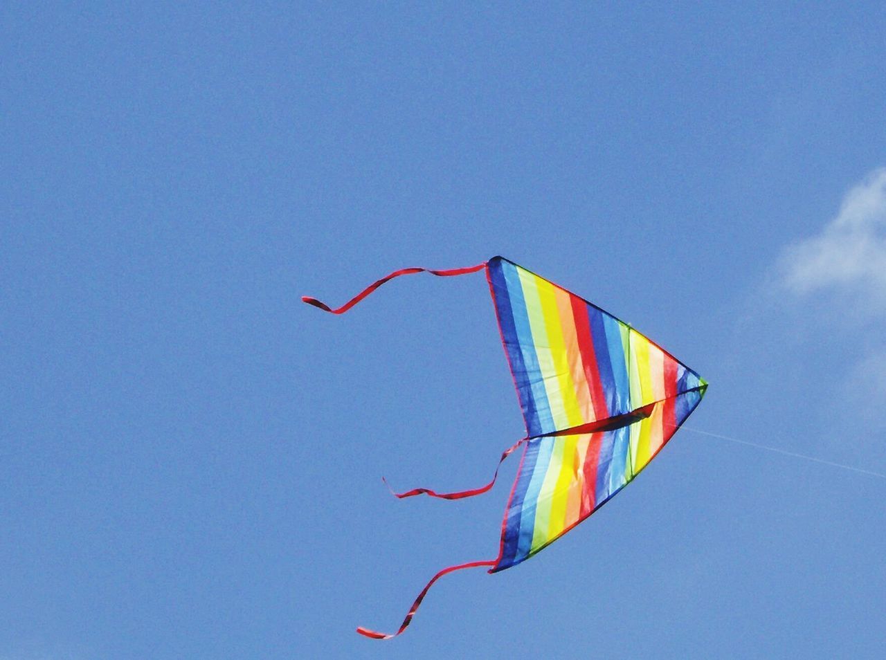 low angle view, blue, multi colored, clear sky, flying, mid-air, flag, copy space, patriotism, colorful, sky, wind, identity, national flag, day, freedom, no people, kite - toy, outdoors, hanging