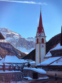 Traditional building by snowcapped mountains against sky