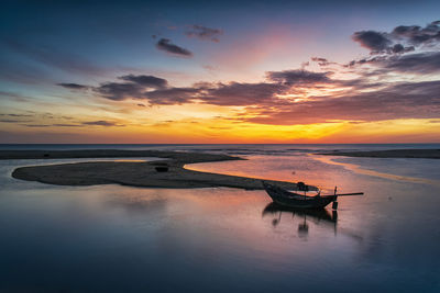 Fishing boat in sea against sky during sunset