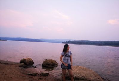 Woman standing at beach against sky