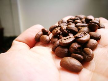 Close-up of hand holding roasted coffee beans