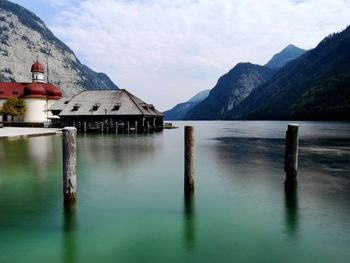 Wooden posts in lake against sky