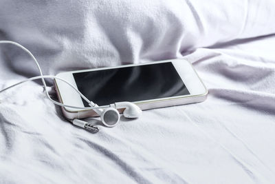 High angle view of mobile phone on bed