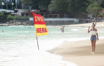 Young woman standing by information sign at beach