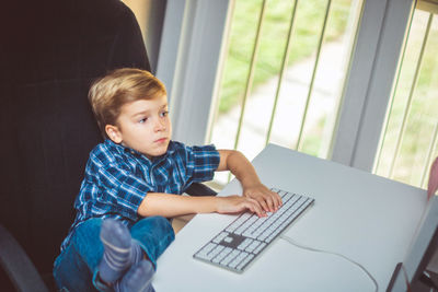 High angle view of boy using computer while sitting at home