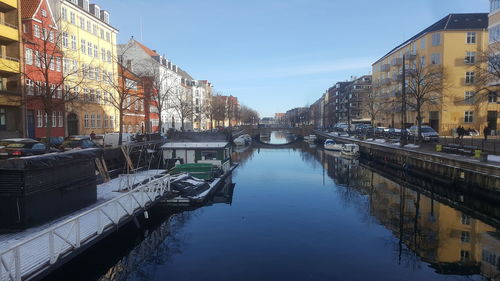 Canal amidst buildings in city against sky