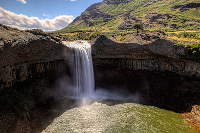 Scenic view of waterfall against sky