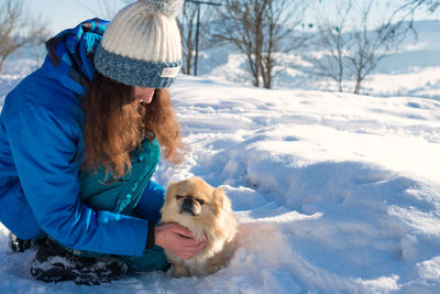 Woman with dog in snow during winter