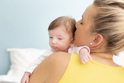 Rear view of mother carrying daughter at home