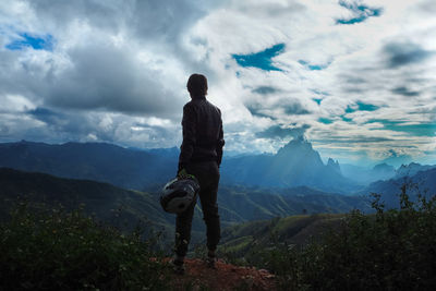 Rear view of man looking at mountain range against sky