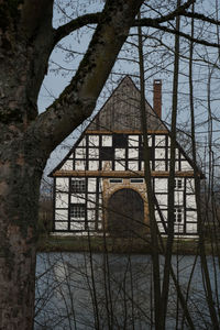 Built structure by bare trees against sky