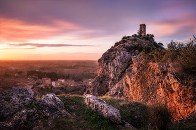 Rock formation on land against sky during sunset