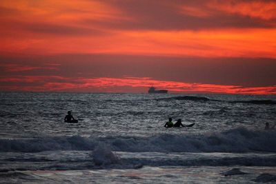 Scenic view of beach against cloudy sky during sunset