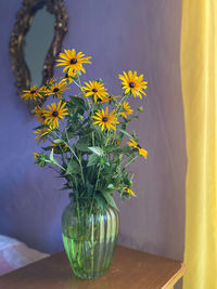 Close-up of yellow flower vase on table against wall