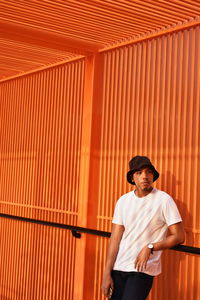 Full length of man standing against orange wall