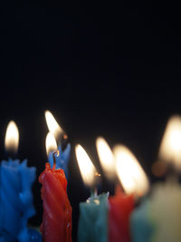 Close-up of illuminated candles against black background