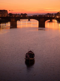 Boat in river against sky during sunset