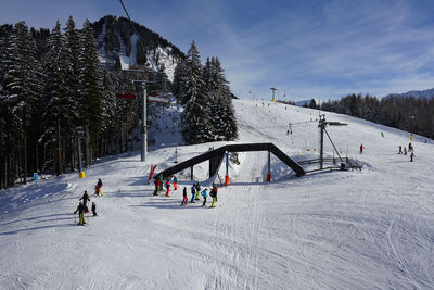 People skiing on snow covered mountain against sky