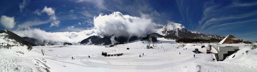 Panoramic view of people on snowcapped mountain against sky