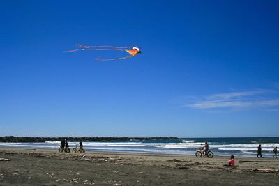 Tourists enjoying on beach against blue sky