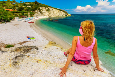 Rear view of woman sitting on beach