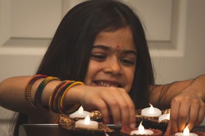 Smiling girl burning diya at home