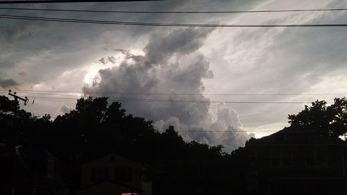 Low angle view of power lines against cloudy sky