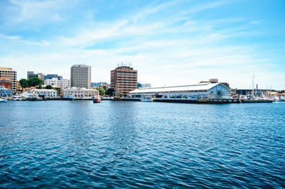 Scenic view of river by buildings against sky