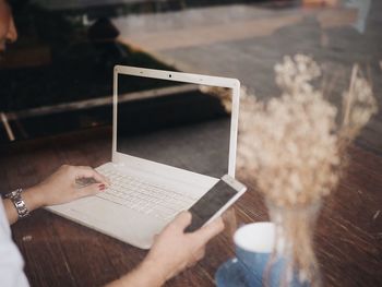 Close-up of woman using laptop on table