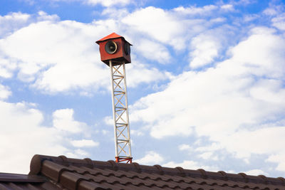 Low angle view of communications tower and building against sky