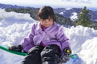 Portrait of smiling girl sitting on snow